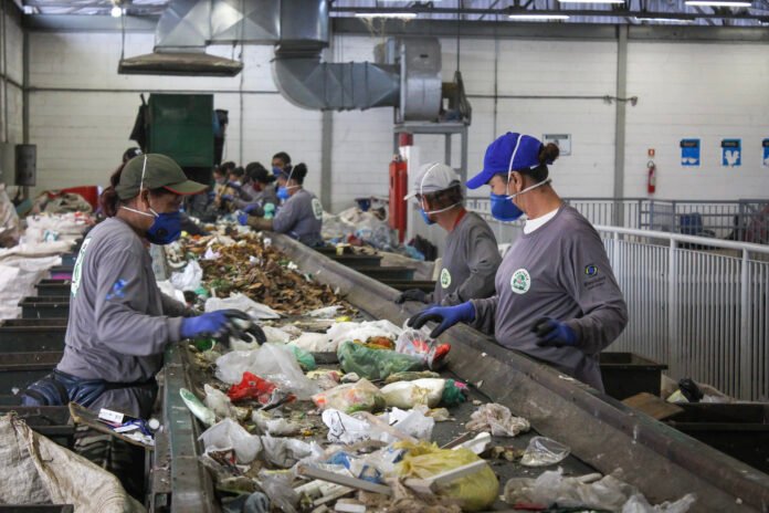 catadores de cooperativa trablhando em esteira de triagem de recicláveis